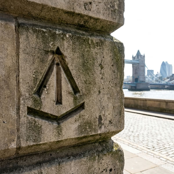 Ordnance Survey benchmark V symbol cut into stonework — marks a precisely known elevation above Ordnance Datum Newlyn